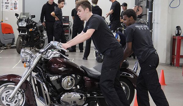 En man arbetar på en motorcykel i ett garage.