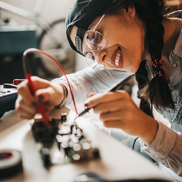 En ung kvinna som arbetar med elektronik i en verkstad.