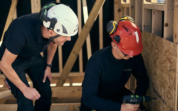 Två män som arbetar på en träkonstruktion.
