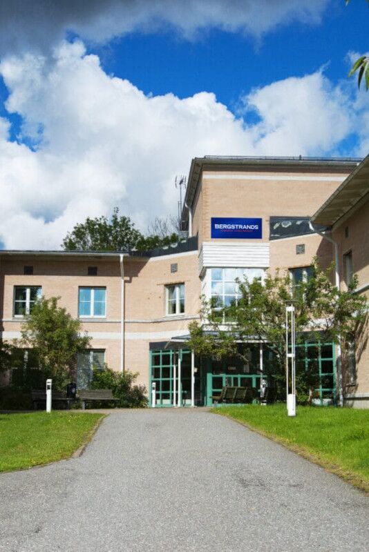 Bergstrands Gymnasium Sigtuna En byggnad med en blå skylt och en gräsyta.