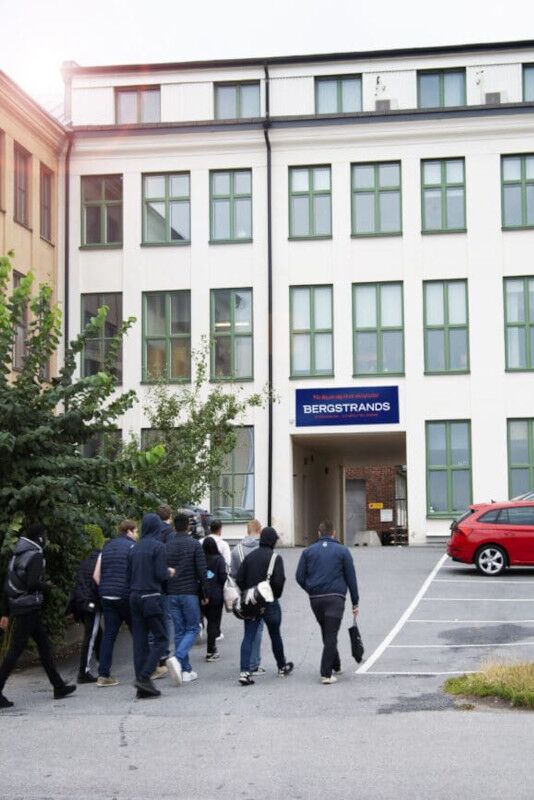 Bergstrands Gymnasium Stockholm En grupp människor som går framför en byggnad.