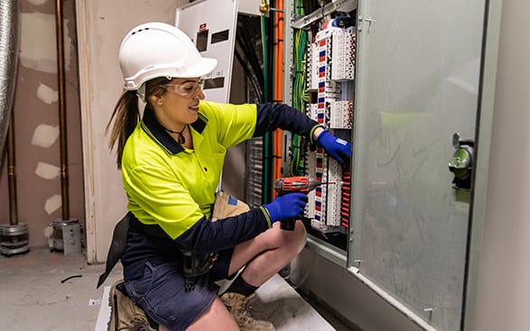 Elektriker som jobbar. En kvinnlig elektriker som arbetar på en elektrisk panel.
