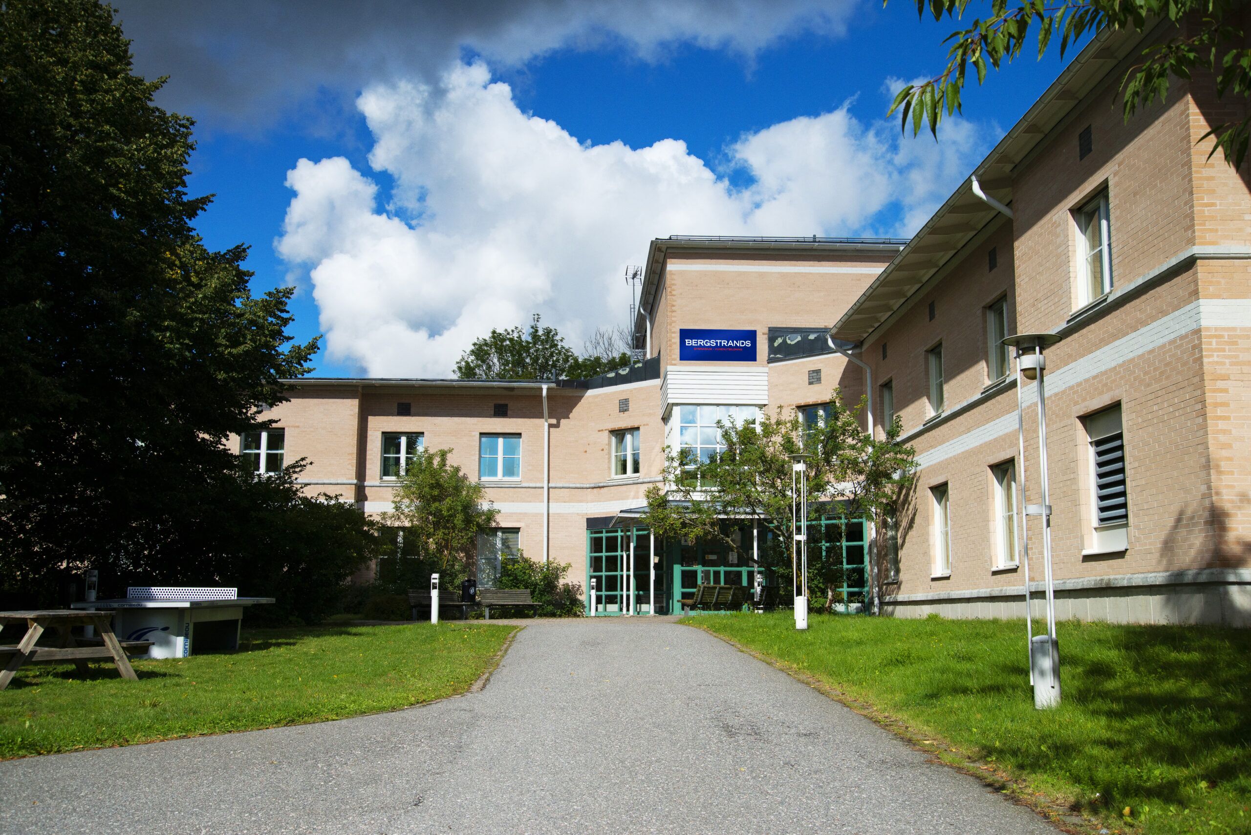 Utsidan av skolan som har en grön glasentré med brun fasad